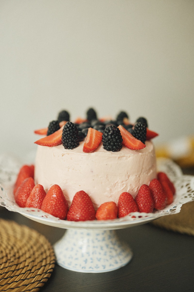 A cake with strawberries and blackberries on top of it