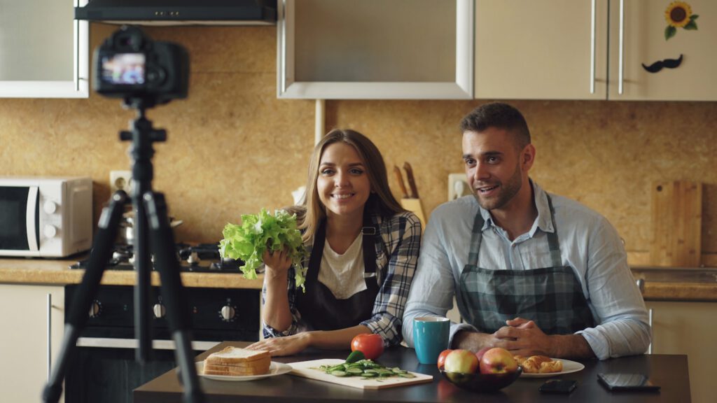 Couple filming cooking show in kitchen